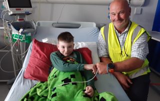 Young patient in bed on ward recovering thanks construction worker who helped him